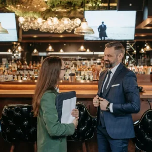 Professional business meeting between a man and woman at a stylish bar setting.