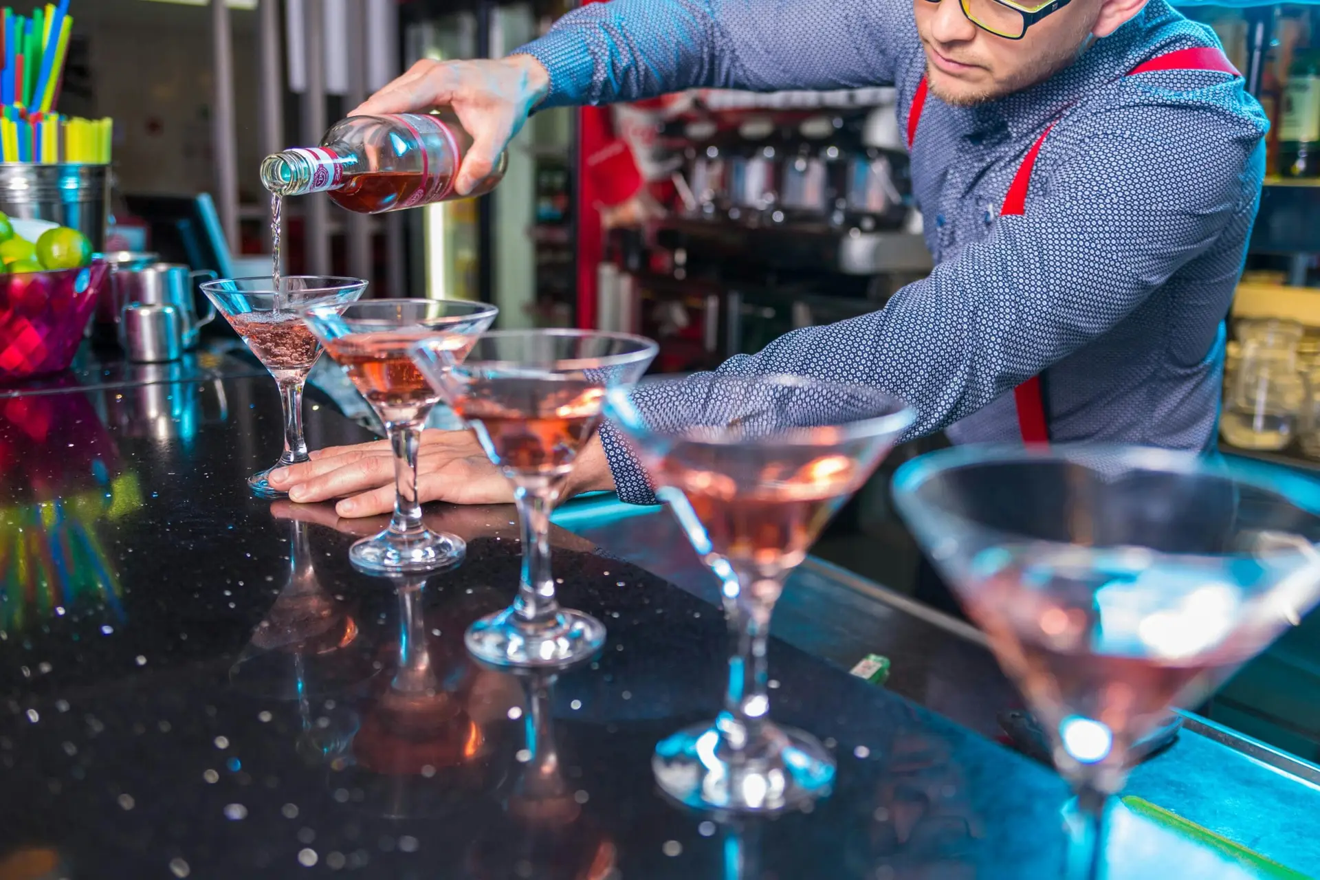 Bartender expertly pours cocktails with finesse at a vibrant indoor bar setting, creating a refreshing party atmosphere.